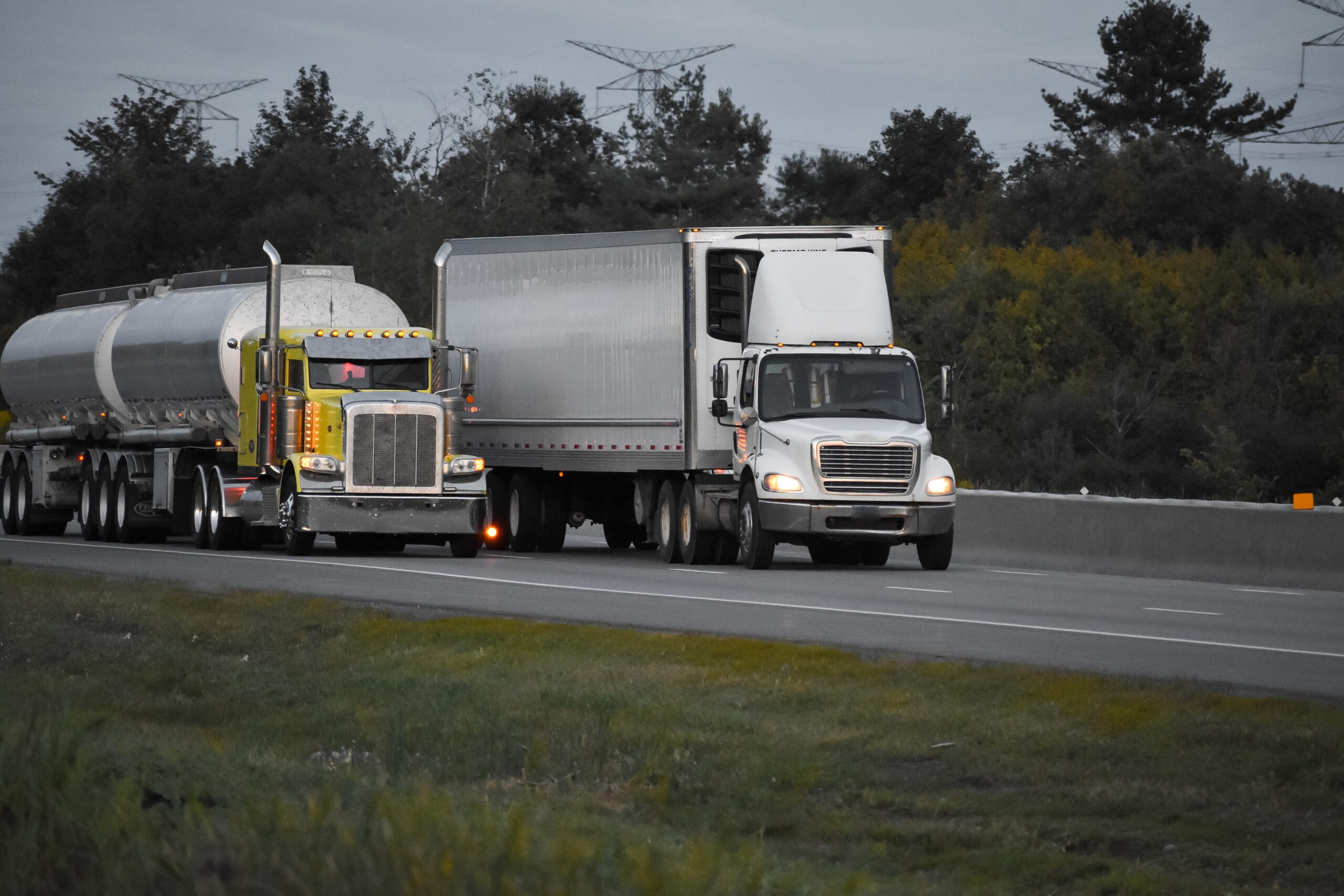 trailer-trucks-driving-road-surrounded-by-beautiful-green-trees Trailer trucks driving