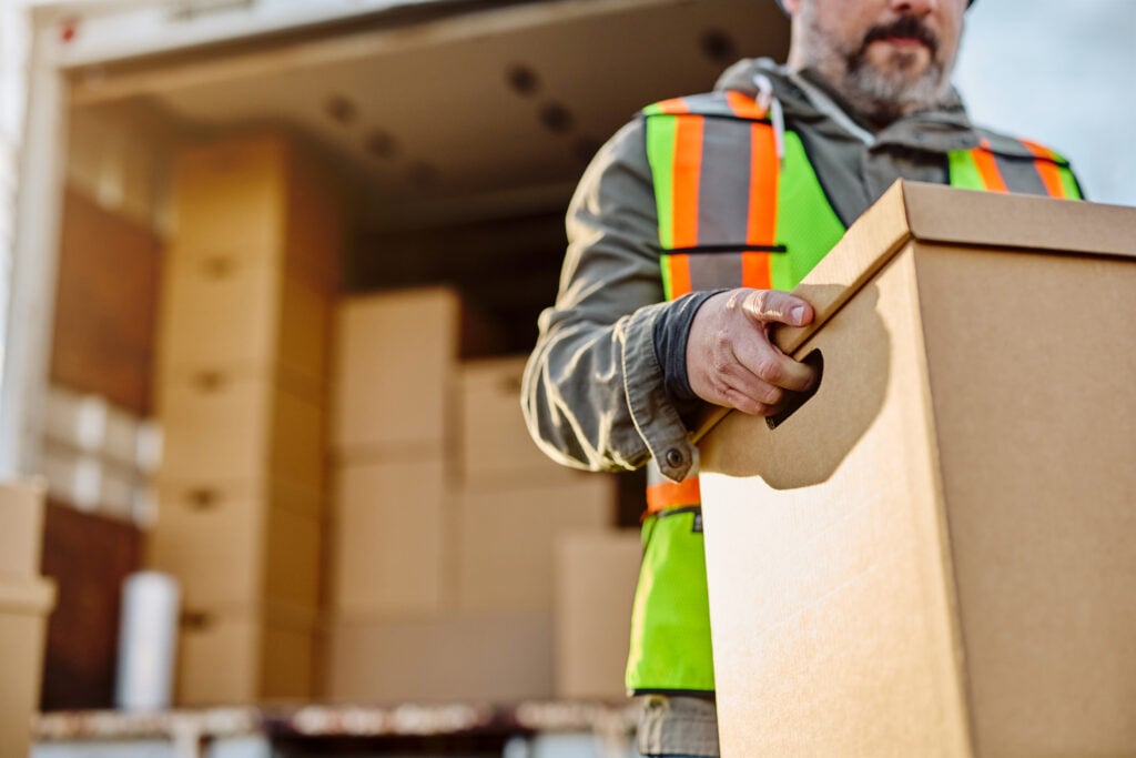 Close up of driver loading carboard boxes into a truck. Close up of driver loading carboard boxes into a truck.